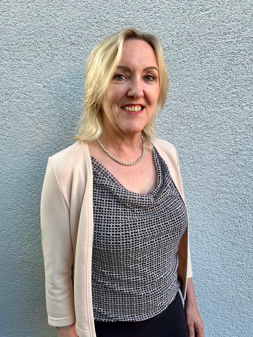 Rosalinde Rech lächelt freundlich vor einer hellen, strukturierten Wand